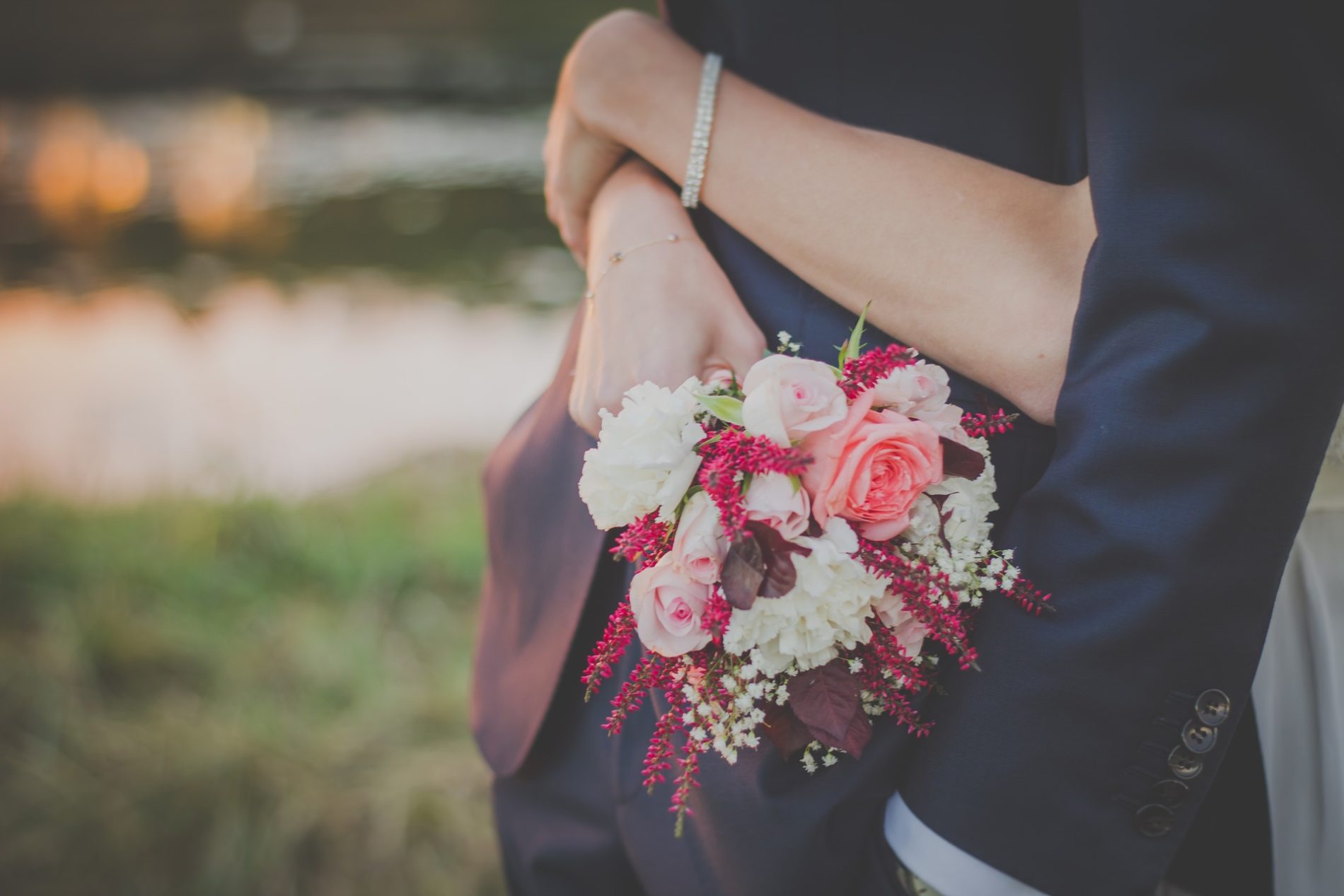 couple de mariés s'enlassant avec bouquet de mariage